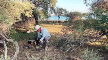 Bir insan, doğanın güzelliği içinde, manzaralı bir su manzarası yakınında gerekli ekipmanları hazırlamakla meşgul.