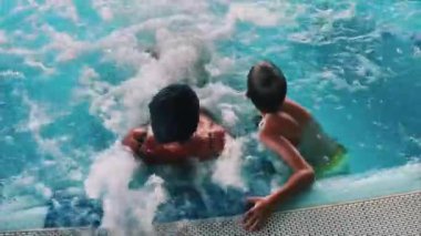 Neşeli aile bağları, güneşin altında canlı ve canlı bir yüzme havuzu sahnesinde paylaşılır.