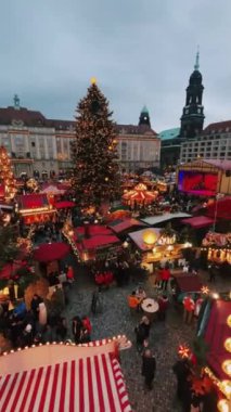 Noel pazarı ziyaretçilerle, süslü ağaçlarla ve akşam gökyüzünün altında hareketli tezgahlarla dolup taşıyor..