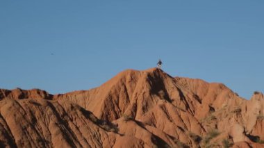 Engebeli, kırmızı bir kaya oluşumunun nefes kesen görüntüsü güzel bir şekilde mavi gökyüzüne karşı kurulmuş.