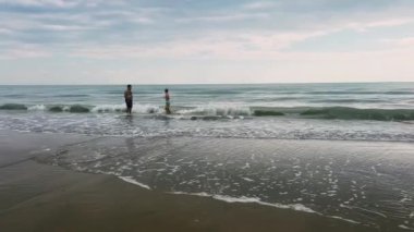 Sevgi dolu bir ebeveyn ve çocuklarının huzurlu sahil şeridinde birlikte oynadıkları güzel ve huzurlu bir an.