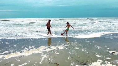 Baba ve oğul mutlu bir şekilde sörf yapıyor güneşli bir plaj gününün tadını çıkarıyorlar.