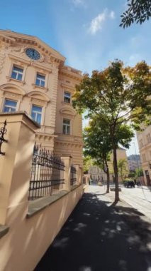 Çok güzel güneşli bir gün. Etrafı canlı yeşilliklerle çevrili zarif, tarihi bir bina sergileniyor.