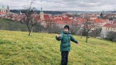 Neşeli bir çocuk, yemyeşil bir tepeden güzel bir kasabanın manzarasının keyfini çıkarıyor.