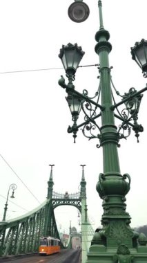 Zarif lambaları ve büyüleyici Budapeşte şehrinde tramvayı olan tarihi bir köprünün çarpıcı manzarası.