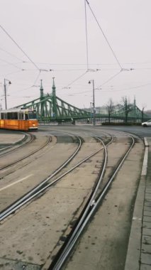 Sersemletici ve büyüleyici manzaralı tramvay rayları bulutlu bir günde yemyeşil bir köprünün yanında birleşiyor.