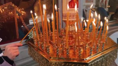 Süslü bir kilise ortamında mumların narin ışığını yakalayan huzurlu bir an.