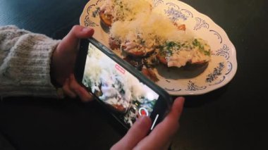 Gurme bir yemeğin fotoğrafını çeken, yaratıcılığı ve modern yemek eğilimlerini sergileyen bir kişi.