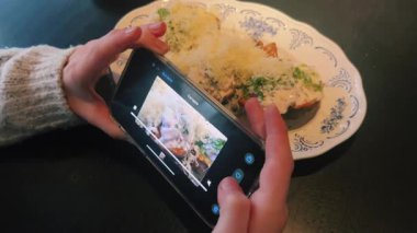 Bir insan nefis yemek sunumu ve yaratıcılığını gösteren güzel bir tabağı fotoğraflıyor.