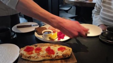 Bir el, modaya uygun bir masada gurme aperatifleri sunuyor, fevkalade lezzetler ve tatlar sunuyor.