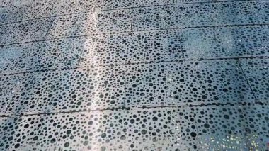 Bu tasarım, izleyicilerin dikkatini çeken, ilgi çekici soyut desenler yaratan dairesel delikler içerir.