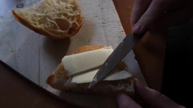 Dikkatli bir el, lezzetli bir somun ekmeğin üzerine ustalıkla kremalı tereyağı sürer.