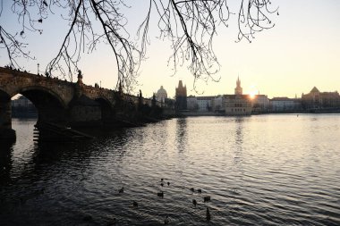 Güzel, sakin bir gün batımı manzarası ikonik Charles Köprüsü Vltava Nehri 'ne ihtişamlı bir şekilde yansıyor.