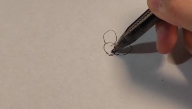 Beyaz kağıda üç bağlı dairesel şekil çizerken, kalem ucu ve çizim sürecine odaklanırken, siyah tükenmez kalem tutan elin yakın çekimi