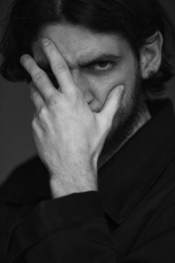 Siyah sakallı ve siyah bıyıklı genç bir adamın portresi.