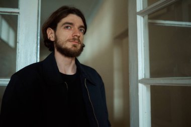 Siyah ceketli genç sakallı adam.