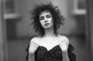 Güzel kıvırcık saçlı, çilli genç bir kadının portresi.