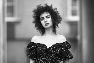 Bir şehrin arka planında kıvırcık saçlı ve makyajlı güzel bir genç kızın portresi.