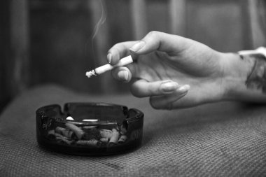Bir adamın ellerinde çakmakla tahta bir arka planda sigara.