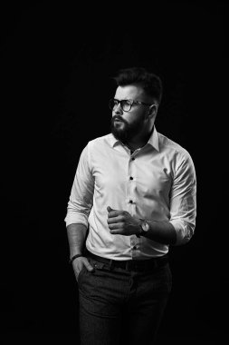 Genç, yakışıklı, sakallı iş adamının siyah ve beyaz arka planda çekilmiş bir fotoğrafı.