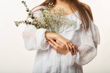 Güzel, genç bir kadın. Elinde çiçekler, açık arkaplanda.