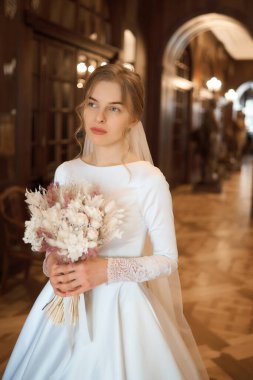 Beyaz elbiseli güzel sarışın gelin elinde bir buket çiçekle