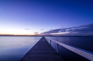 Aydınlatılmış Central Coast Uzun Jetty Sakin Gece Sularına Geriniyor Şehir Işıklarını Yansıtan