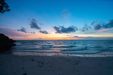 Boracay plajında gün batımı kızıl bulutlar ve sakin deniz kıyısında.