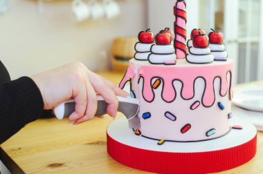 Karikatür tarzında güzel bir pasta, mum ve kirazla parlak, yakın çekim bir bölümde yapılır.