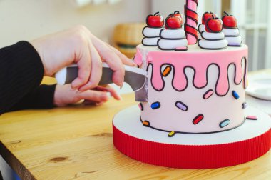 Karikatür tarzında güzel bir pasta, mum ve kirazla parlak, yakın çekim bir bölümde yapılır.