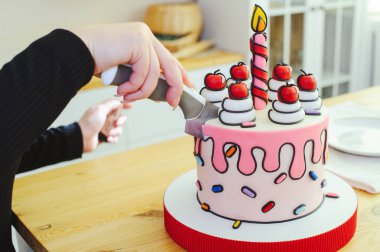 Karikatür tarzında güzel bir pasta, mum ve kirazla parlak, yakın çekim bir bölümde yapılır.