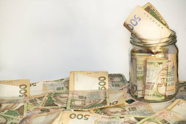 Banknotlar cam bir kavanozda ve masanın üzerinde, mesaj için oda, beyaz arkaplan, UAH