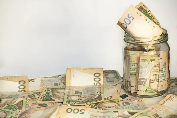 Banknotlar cam bir kavanozda ve masanın üzerinde, mesaj için oda, beyaz arkaplan, UAH