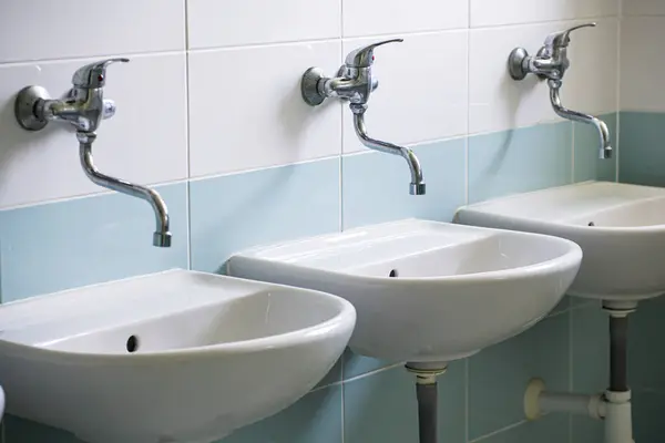 stock image Public washroom with white ceramic washbasins, close-up.