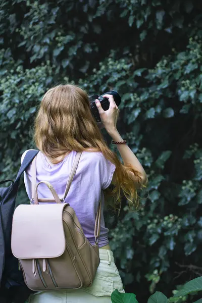Uzun sarı saçlı, elinde fotoğraf makinesi olan Avrupalı bir bayan turist fotoğraf çekiyor..