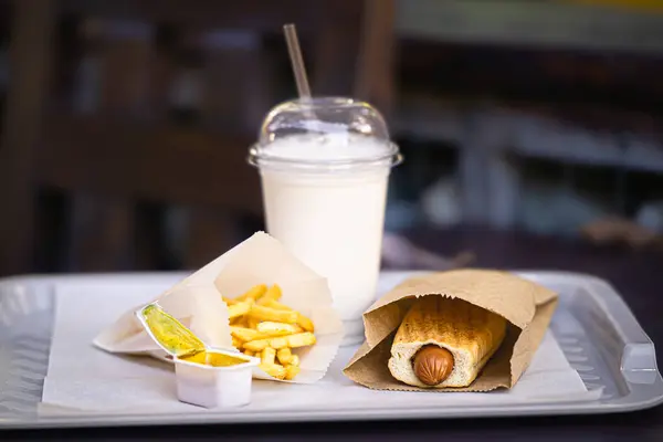 Kızartma, milkshake ve Fransız sosislisi, tepside fast food restoranından bir set..