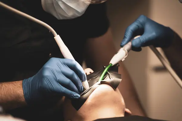 Bir doktor ve asistanı hastanın dişlerini, doğal durumlarını, dişçiliğini tedavi eder..