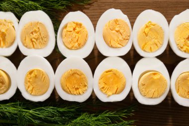 Haşlanmış tavuk yumurtaları ikiye ayrılır ve yeşilliklerin yanındaki tahtanın üzerine serilir..