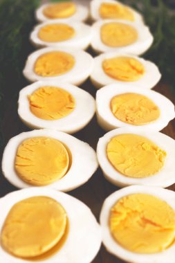 Haşlanmış tavuk yumurtaları ikiye ayrılır ve tahta bir tahtaya dizilir..