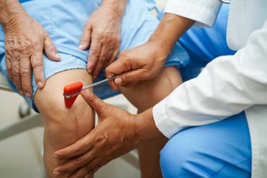 Doktor nörolog çekiçle refleks dizini test ediyor ve Asya 'nın son sınıf yaralarını gösteriyor.. 