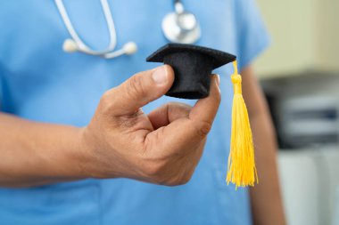 Asyalı doktor mezuniyet şapkası ve eğitim ilacı taşıyor..