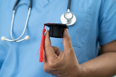 Asyalı doktor mezuniyet şapkası ve eğitim ilacı taşıyor..