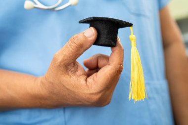 Asyalı doktor mezuniyet şapkası ve eğitim ilacı taşıyor..