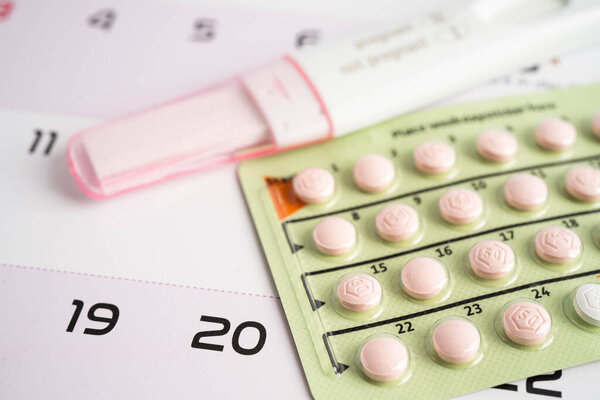Pregnancy test and birth control pills on calendar, contraception health and medicine.
