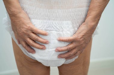 İdrar tutamama kontrolü için bez takan Asyalı yaşlı kadın..