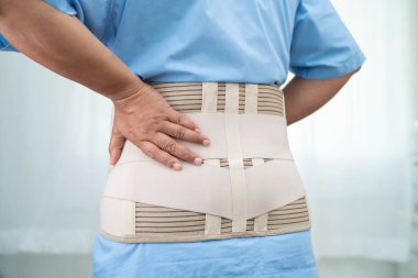 Ortopedik bel kemiği için sırt ağrısı destek kemeri takan Asyalı bir kadın hasta..