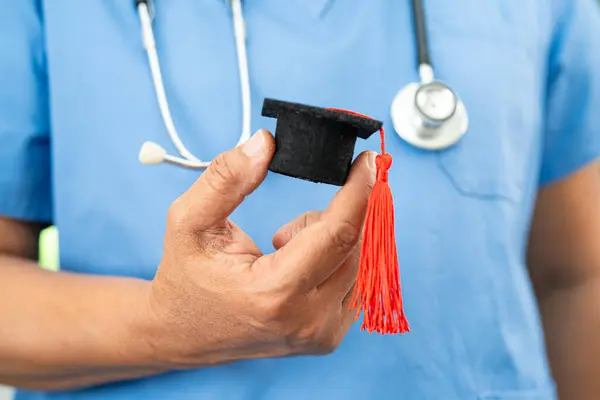 stock image Asian doctor holding graduation gap hat, education medicine.