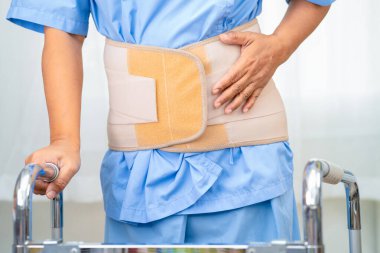 Ortopedik bel kemiği için sırt ağrısı destek kemeri takan Asyalı bir kadın hasta..