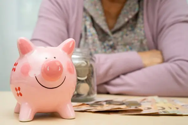 Emekli maaşı, sigortası, yoksulluğu ve finansal sorunu için pembe domuz kumbarası olan Asyalı yaşlı kadın..