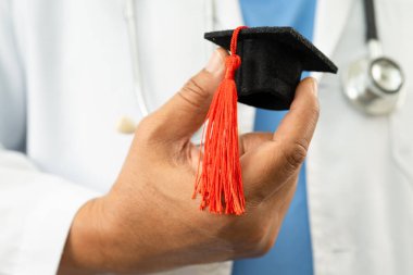 Asyalı doktor mezuniyet şapkası ve eğitim ilacı taşıyor..